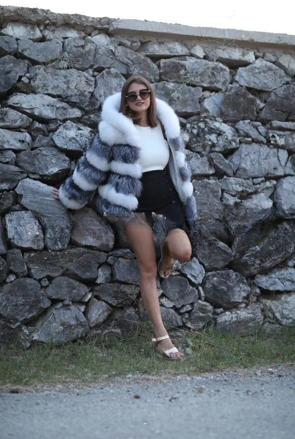 A woman wearing a loose-fit brown artificial fur hooded coat of medium length.