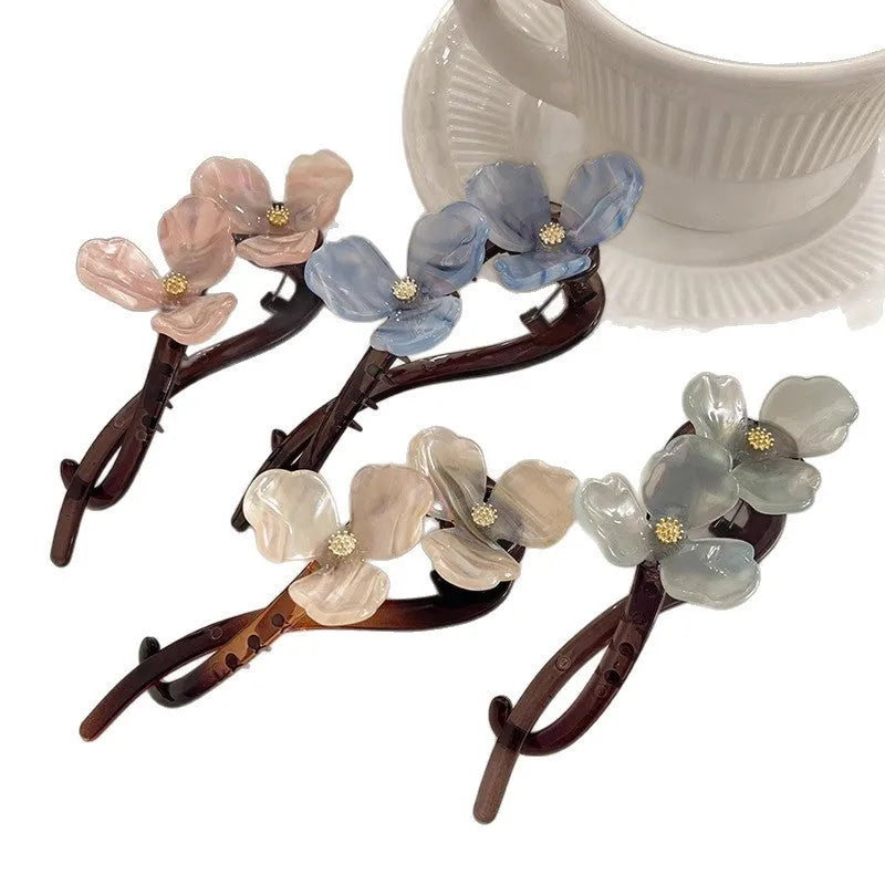 Close-up of a retro-style floral bobby pin with coloured acrylic petals.