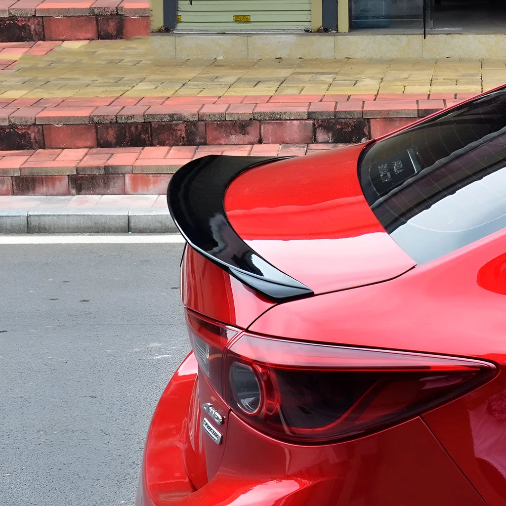 Bright black aftermarket tail trim spoiler for a Mazda 3 car rear bumper.