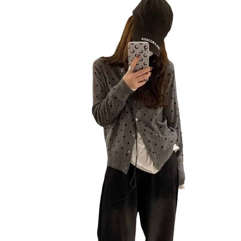 Women's grey knitted cardigan with white crochet flower embroidery on the front.