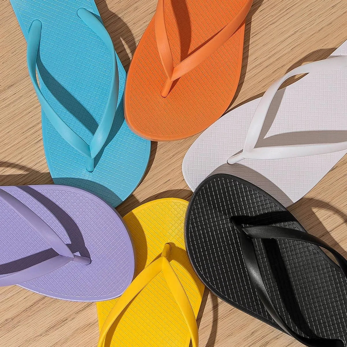 Flat casual slippers with plastic upper and non-slip PVC sole in orange, purple, black, and white colours.