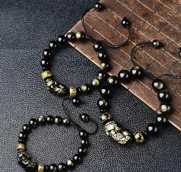 Hand-woven golden obsidian Pi Xiu bracelet with animal zodiac charm on wrist.