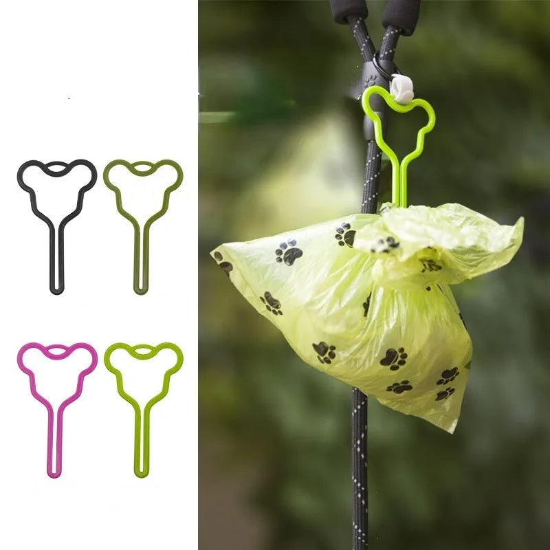 A hands-free dog poop bag holder with a black plastic clip and adjustable velcro strap, loaded with green waste bags.