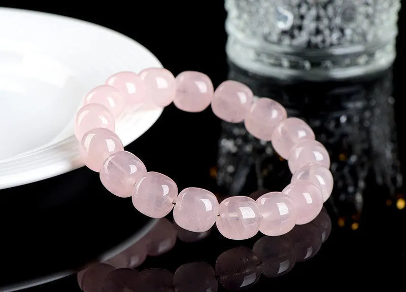 Close-up of a pink crystal bracelet with barrel-shaped beads on a wrist.