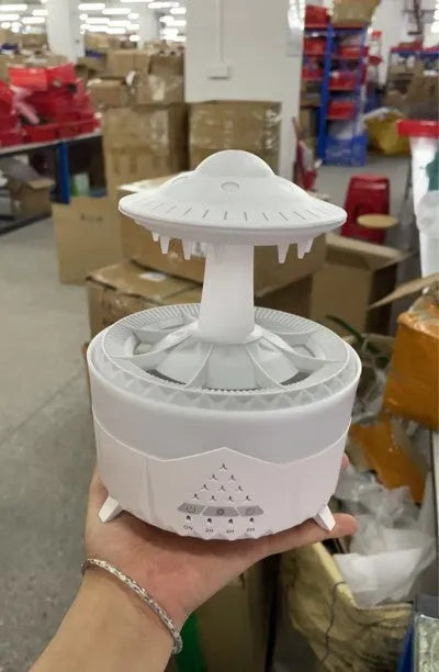 White cloud-shaped humidifier with water droplets and coloured lights on wooden surface