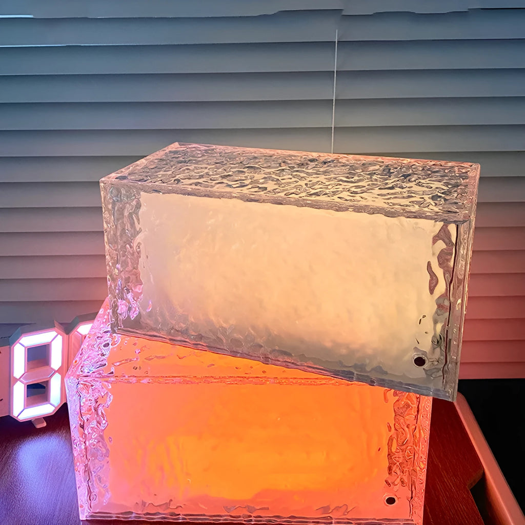 Geometric clear acrylic small night lamp with coloured LED light on a table.