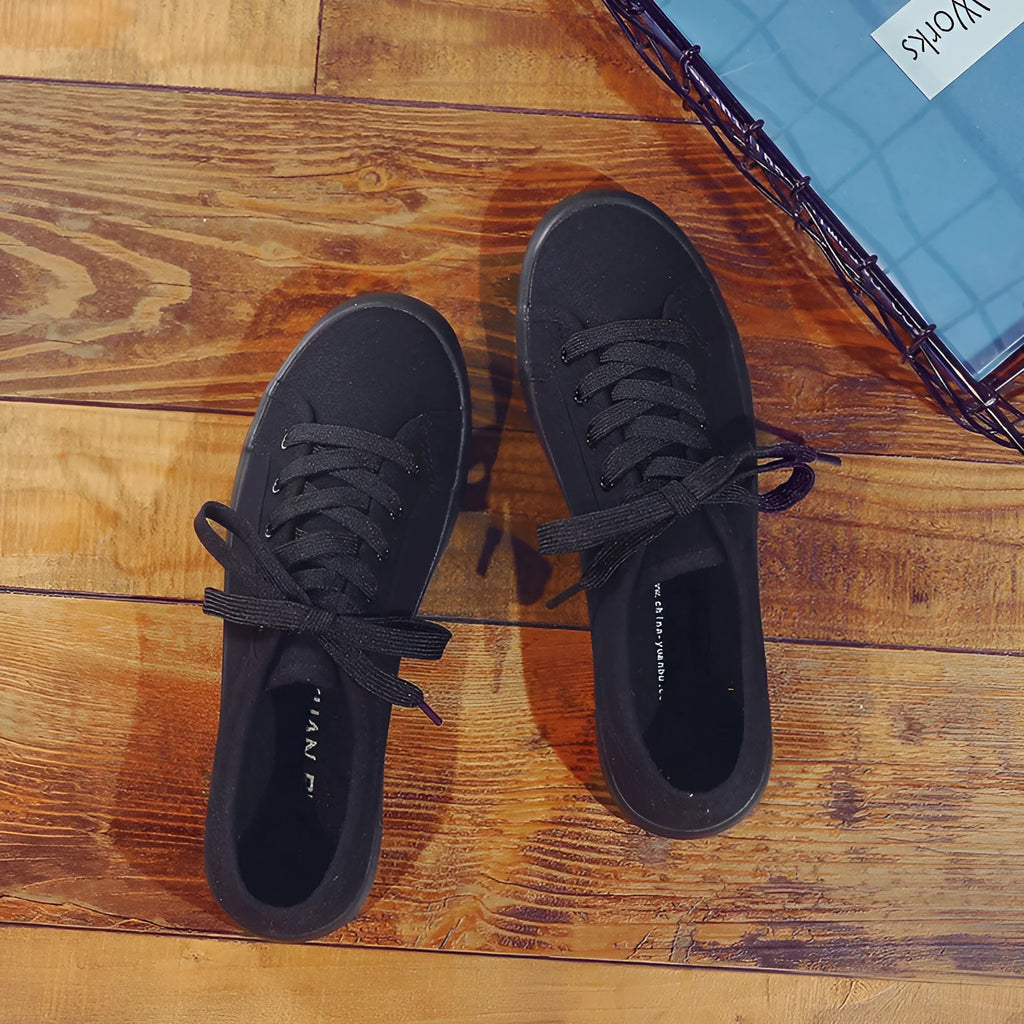 Women's all-black canvas flat lace-up shoes with a slim profile and rubber sole.