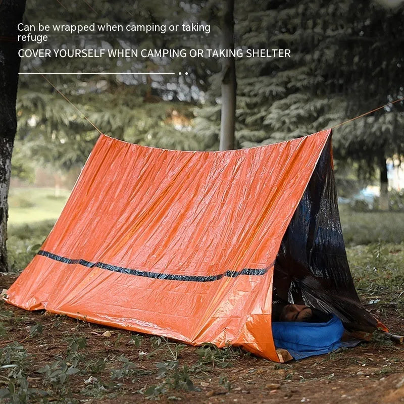Orange and green emergency tent, sleeping bag, and raincoat kit for outdoor survival.