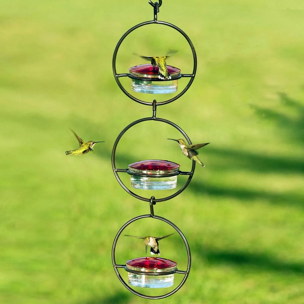 Metal round hanging hummingbird feeder in black with perch and nectar ports on outdoor hook