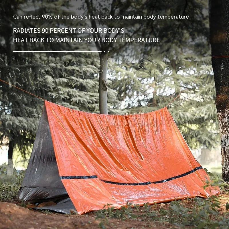 Orange and green emergency tent, sleeping bag, and raincoat kit for outdoor survival.