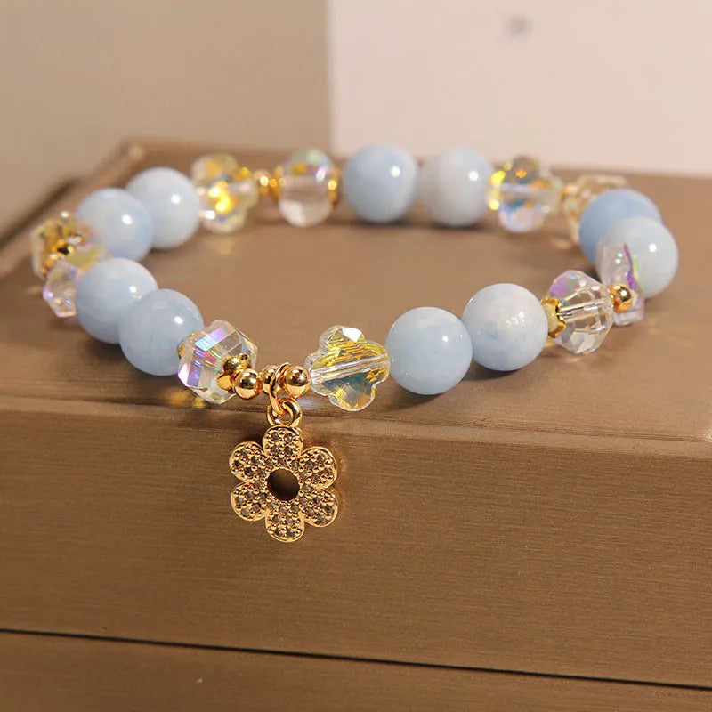 Women's aquamarine crystal bracelet with a four-leaf clover charm and pearl detail.