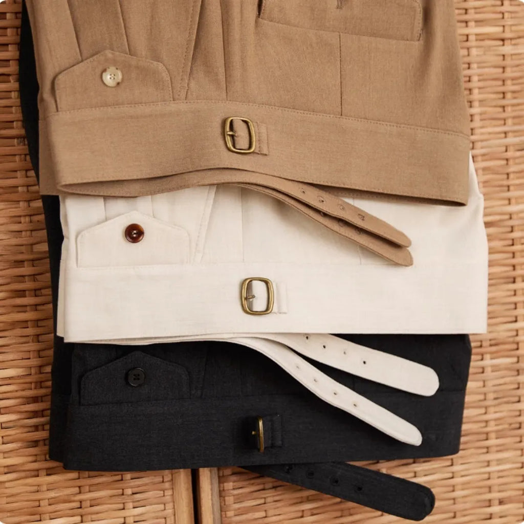 Men's slim fit straight leg trousers in dark grey, light brown, and light apricot colours on a hanger.