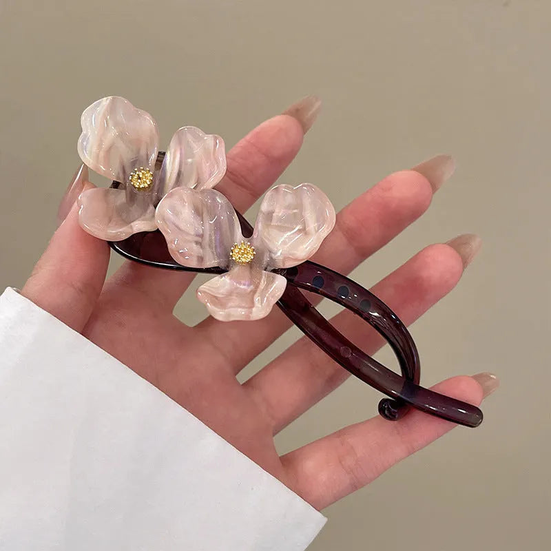 Close-up of a retro-style floral bobby pin with coloured acrylic petals.