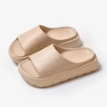 Women's beige fish mouth style slippers with a thick EVA sole on a wooden floor.