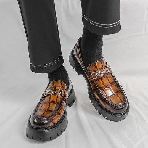 Men's black crocodile pattern loafers with a flat platform sole on a plain background.