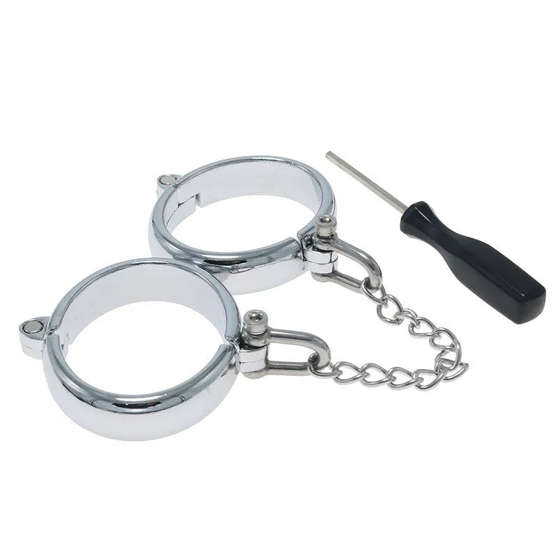 Silver zinc alloy metal handcuffs and footcuffs set for adult bondage play on a dark background.