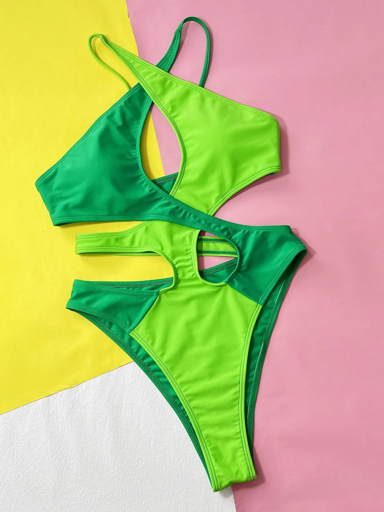 Green women's one-piece swimsuit with a contrast hollow design on a mannequin.