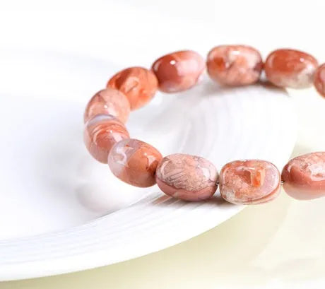 Natural cherry agate bracelet with barrel-shaped beads and a gold Ruyi charm on an adjustable strap.