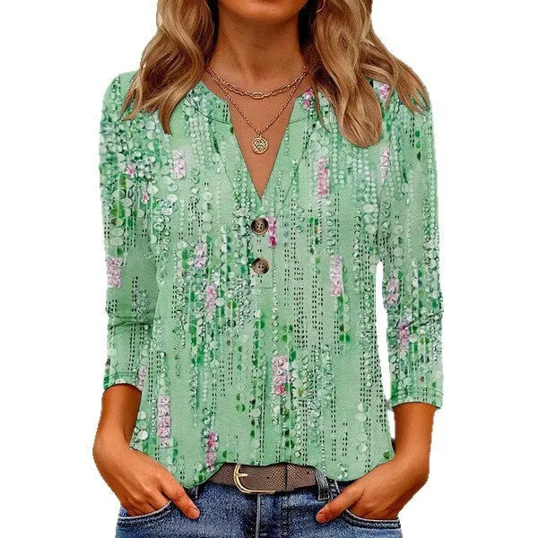 Woman wearing a loose-fit grey V-neck top with a colourful 3D geometric pattern print.
