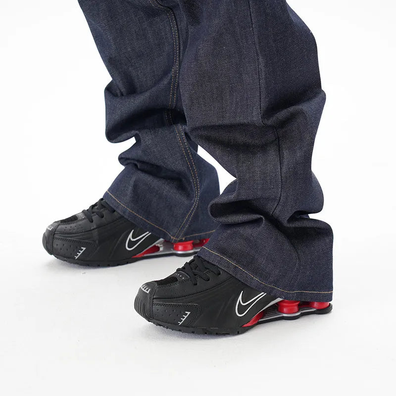A pair of dark blue loose straight-cut jeans laid flat, showing the front design.
