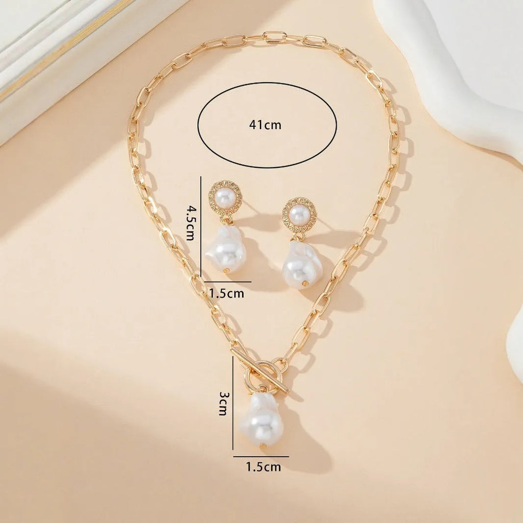 Gold-tone baroque pearl pendant necklace and matching stud earrings set on a white background.