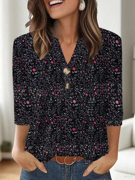 Woman wearing a loose-fit grey V-neck top with a colourful 3D geometric pattern print.