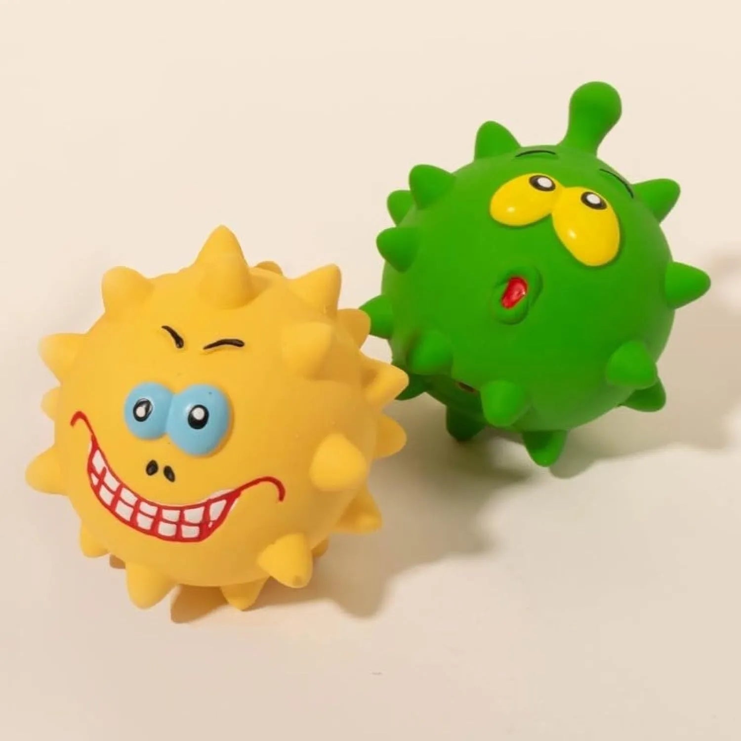 Four colourful squeaky dog balls with cute faces made from natural latex rubber