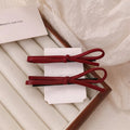 Wine red leather bow hair barrette on a white background.
