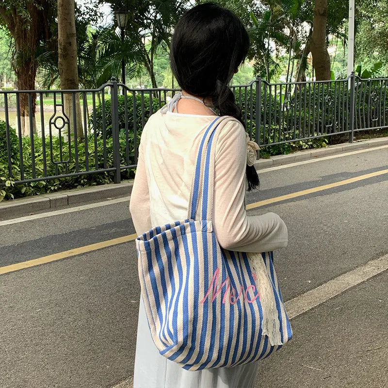 Pink cotton canvas bag with a printed design of blue and white striped letters.