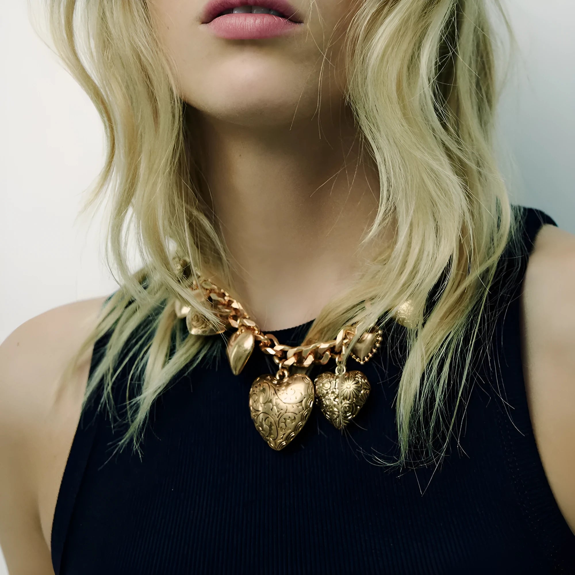Exaggerated style gold heart pendant necklace with a regular chain on a plain background.