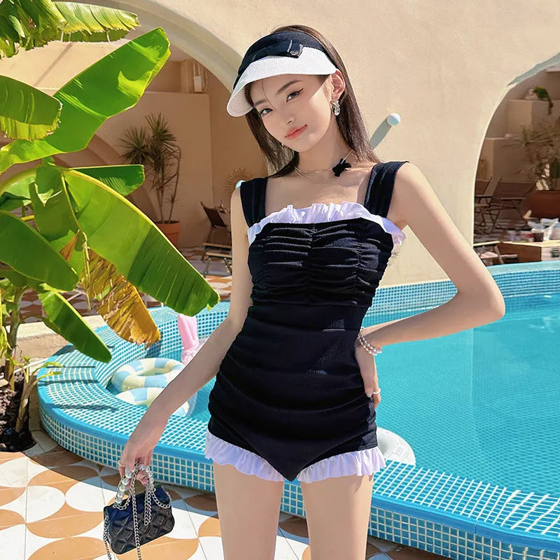 Women's solid pink one-piece swimsuit with black suspender straps on a mannequin.
