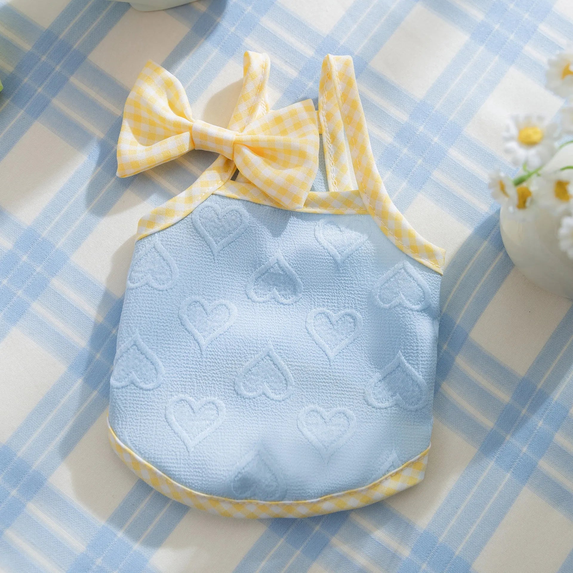 Small dog wearing a blue heart relief texture vest with bow suspenders and a matching hairband.