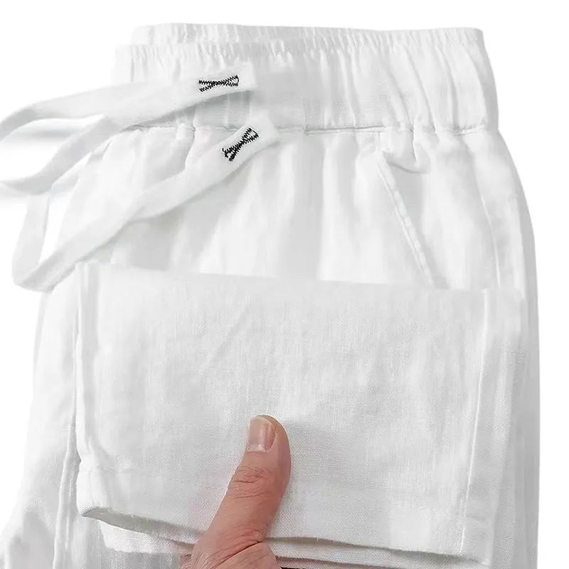 A pair of straight-leg linen trousers in a neutral colour with a visible drawstring elastic waistband.
