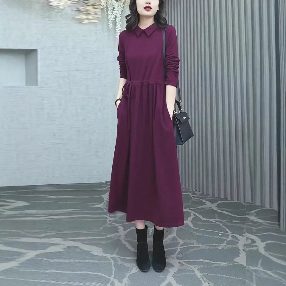 A purplish red plus size long sleeve midi dress for women, shown in an urban style.