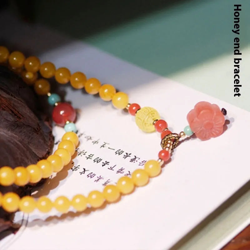 Yellow chicken grease coloured amber bracelet with animal zodiac charm on a white background.