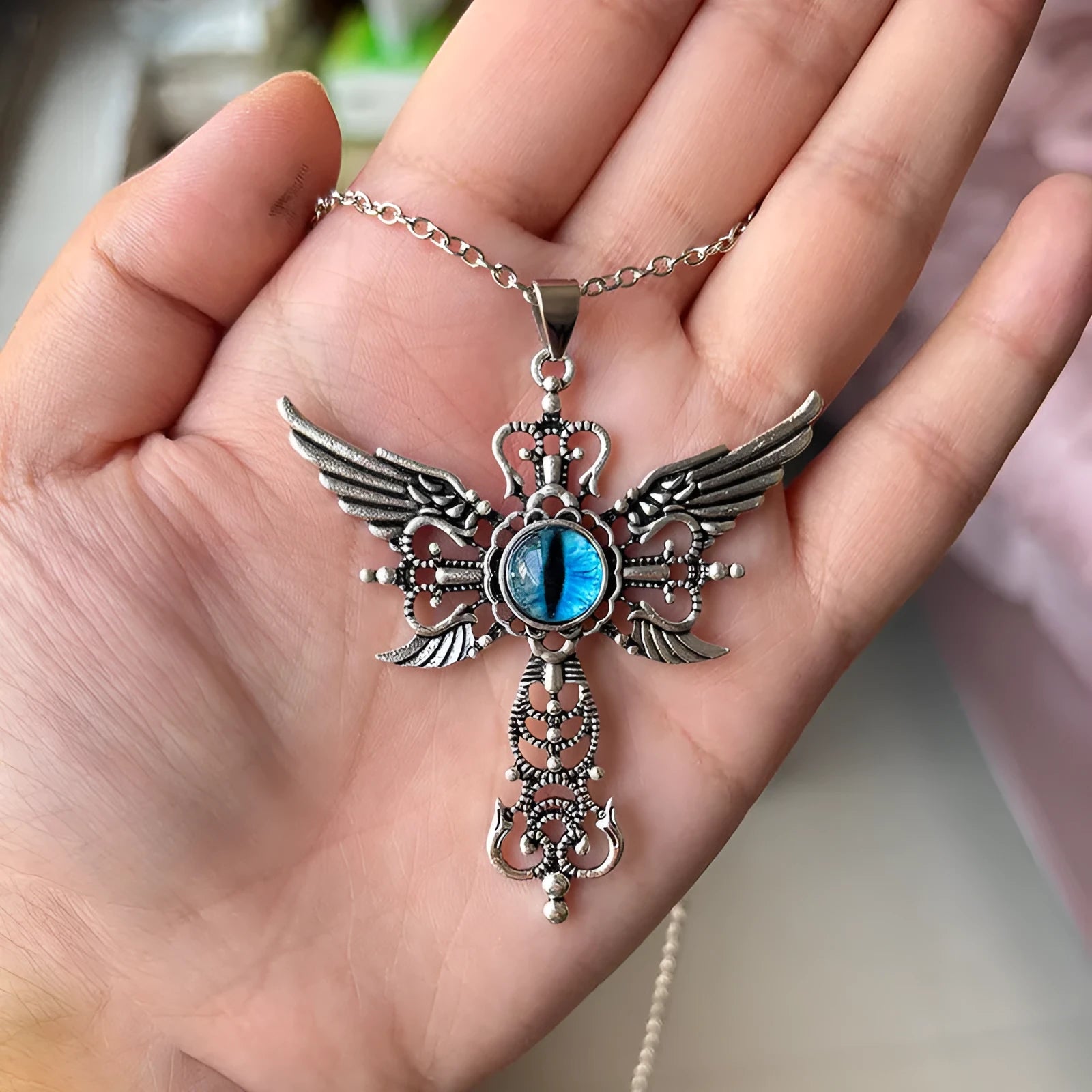Geometric alloy pendant necklace featuring detailed devil wings and a cross, shown in multiple colour options.