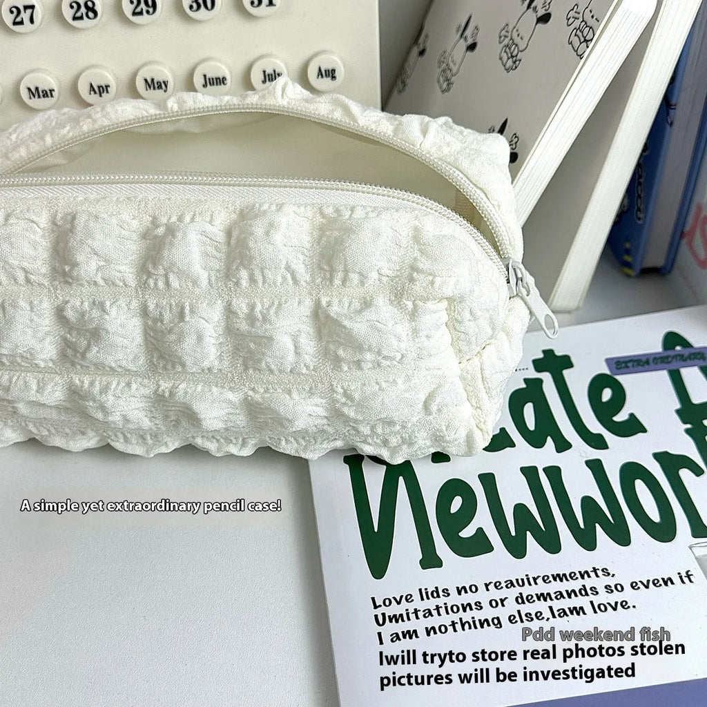 Beige and black fabric cream puff style pencil case made from polyester.