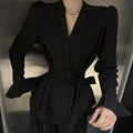 Women's black shirt with an irregular collar and long bell sleeves on a model.