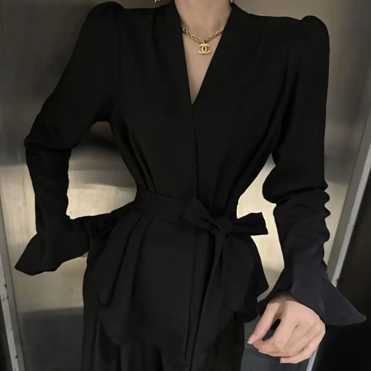 Women's black shirt with an irregular collar and long bell sleeves on a model.