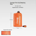 Orange and green emergency tent, sleeping bag, and raincoat kit for outdoor survival.