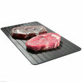 Black rectangular aluminium fast defrost tray for thawing frozen food on a kitchen counter.