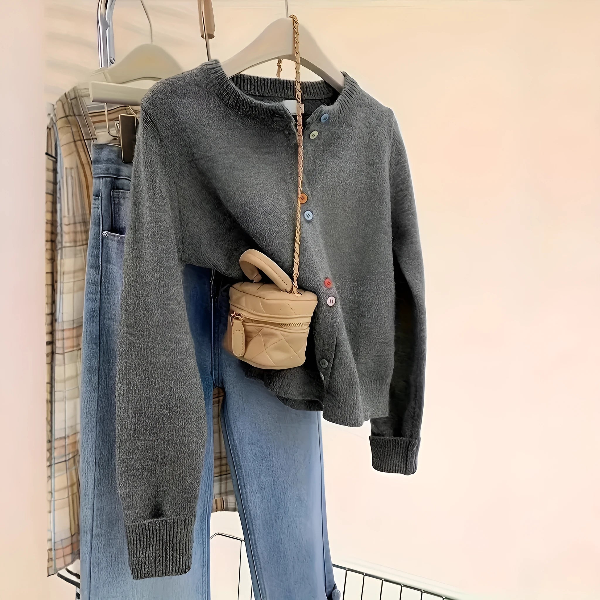 Dark grey women's button-front cardigan sweater with long sleeves on a hanger