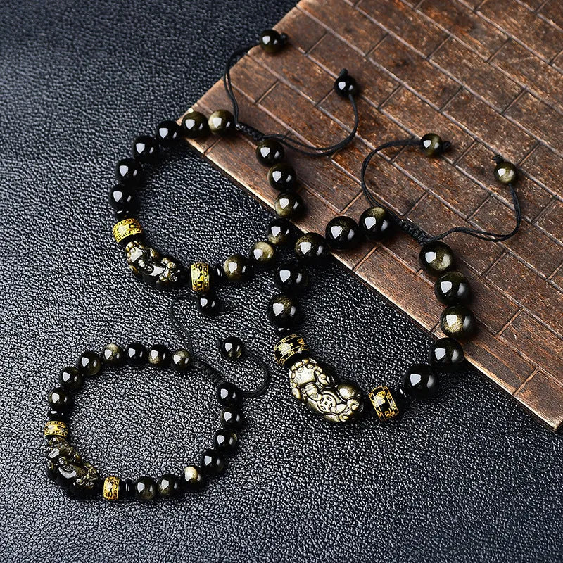 Hand-woven golden obsidian Pi Xiu bracelet with animal zodiac charm on wrist.