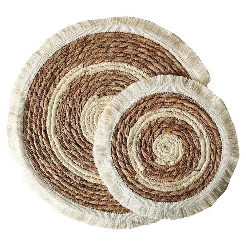 Round natural papyrus placemat on a wooden table, showing corn rope tassel detail and modern minimalist style.