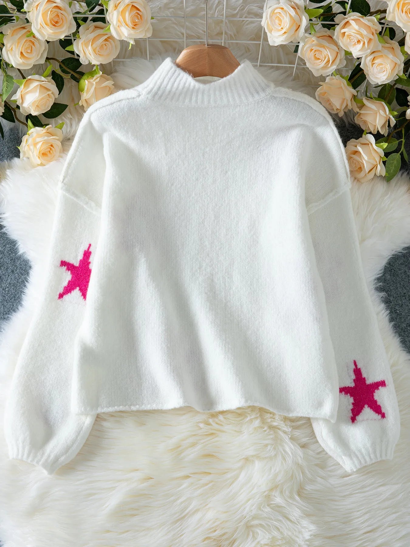 White women's loose turtleneck pullover with a black five-pointed star pattern on the front.