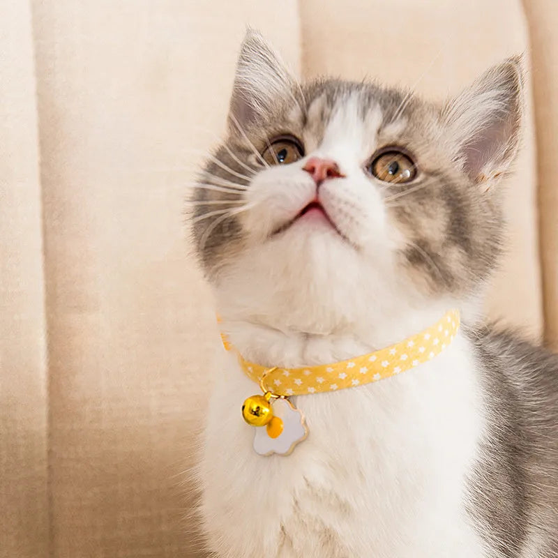Adjustable green cat collar with a metal bell pendant and a matching bow tie decoration.