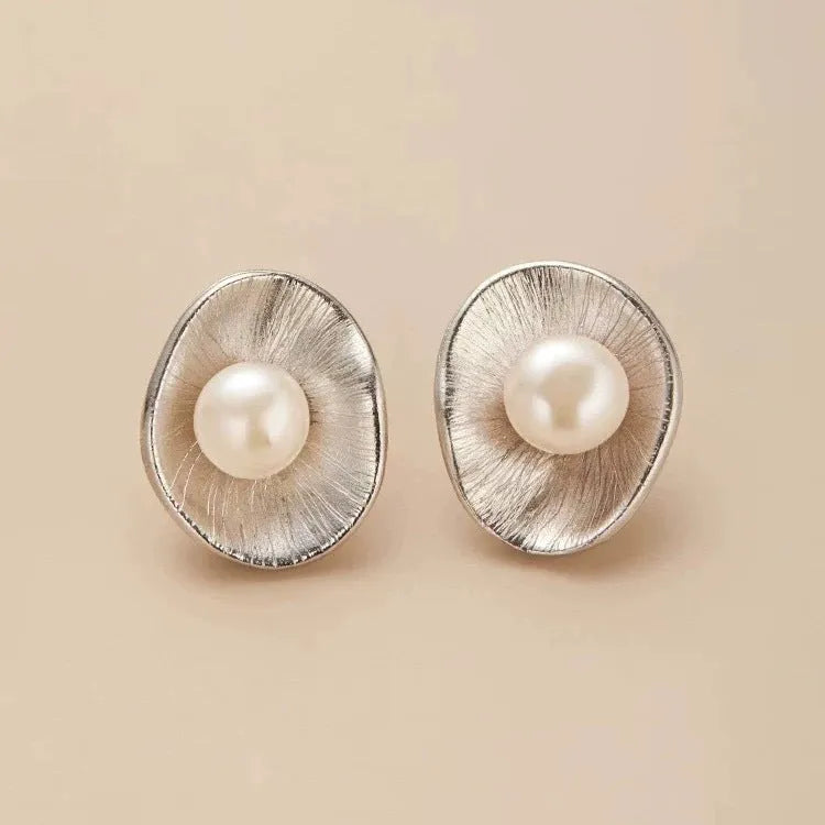 A pair of geometric sterling silver ear studs with pearl accents and a gold electroplated finish.