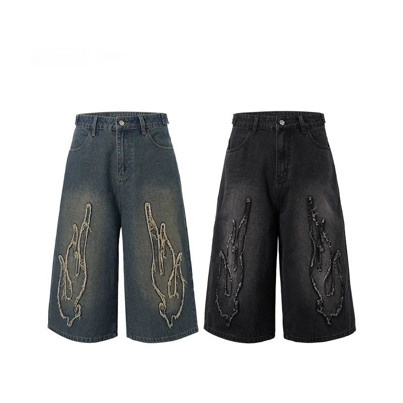 Men's black denim shorts with cropped length and flame embroidery patch design on leg