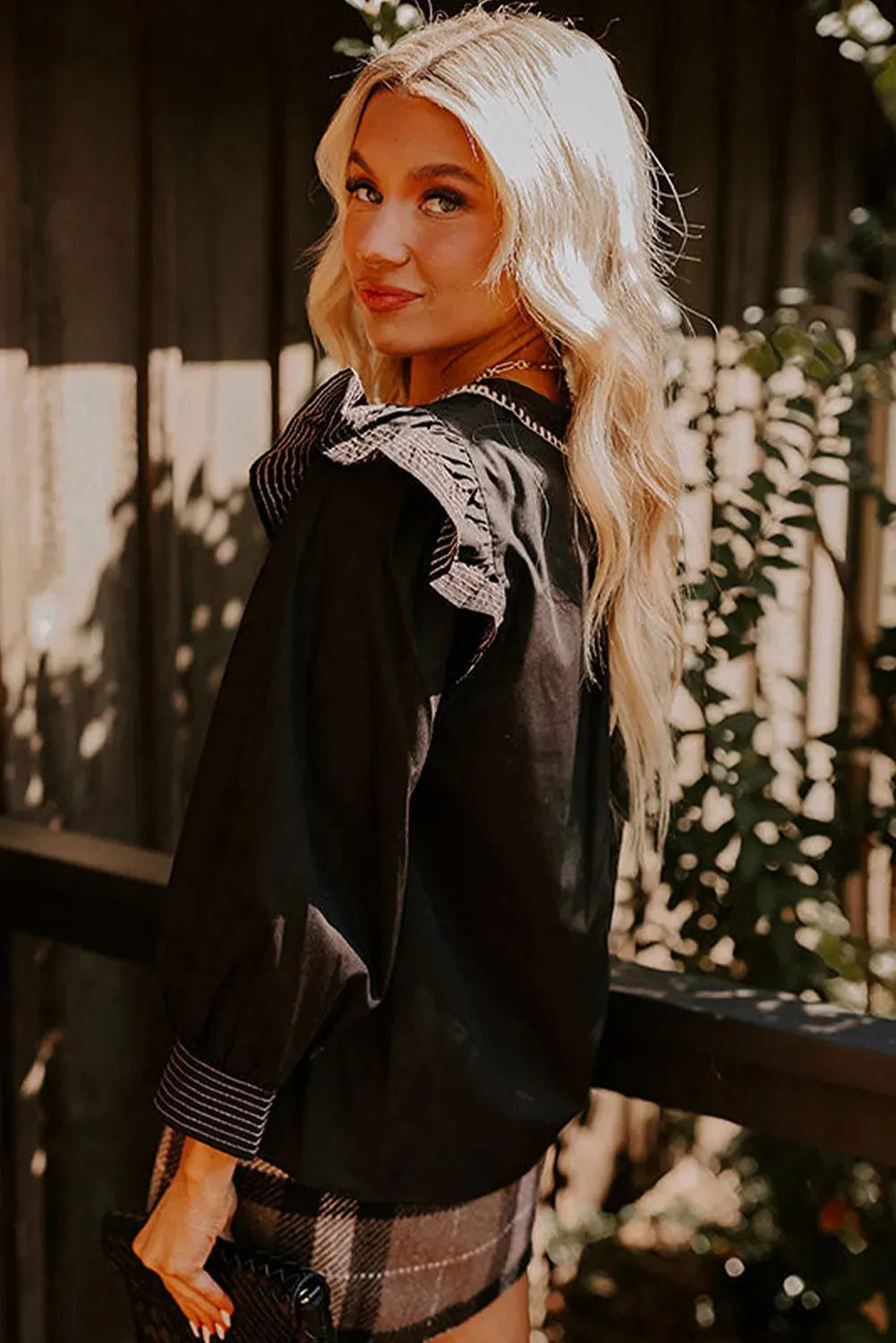 Black V-neck long sleeve blouse with contrast stitching and ruffle trim on sleeves