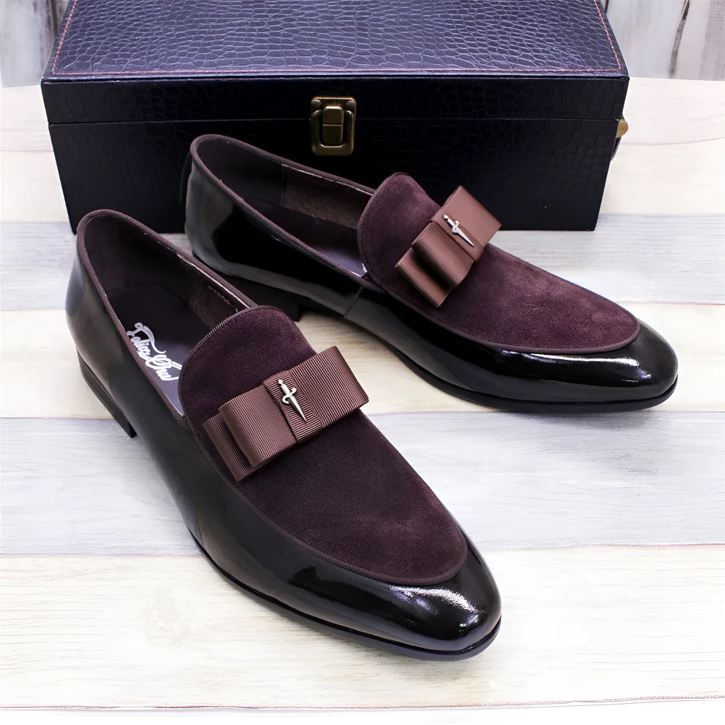 Men's glossy black patent leather low-top shoes featuring a gold tassel detail on a white background.